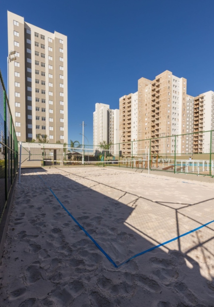 Quadra de areia e torres de apartamentos, área de lazer do condomínio