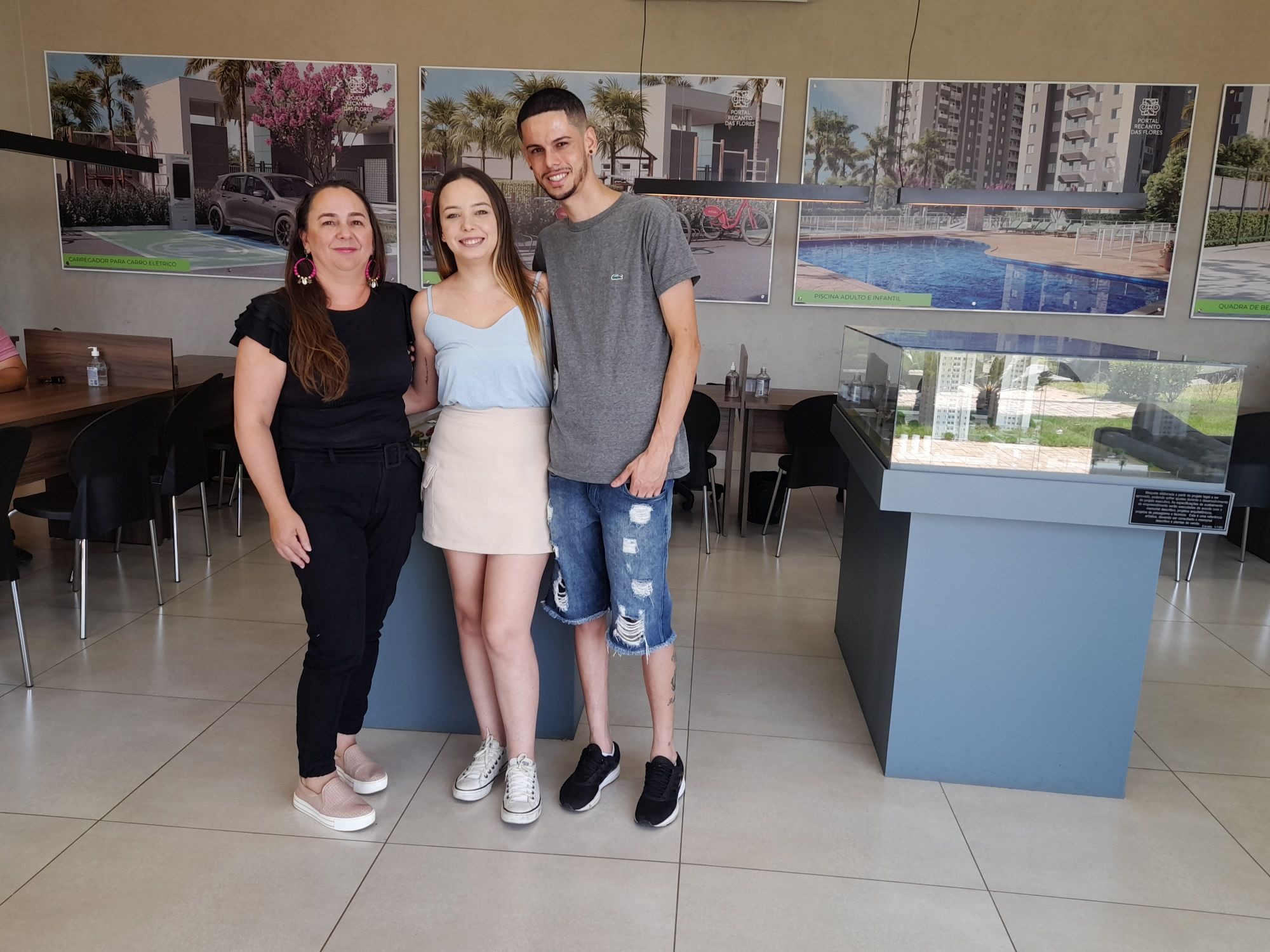 Karina Aguiar com clientes diante da maquete de um empreendimento BRZ