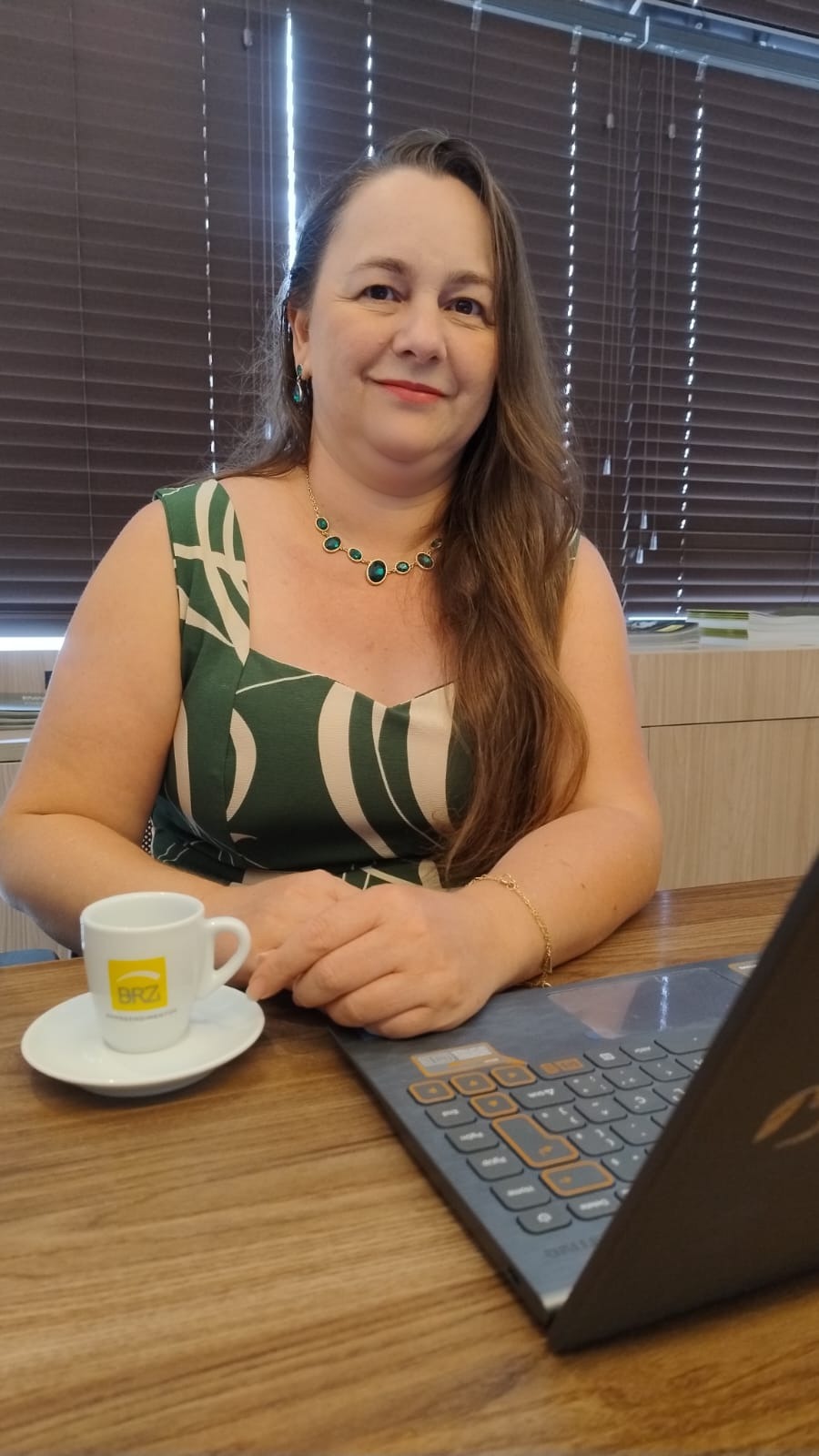 Karina Aguiar, corretora de imóveis, em atendimento com o notebook e uma xícara da BRZ Empreendimentos